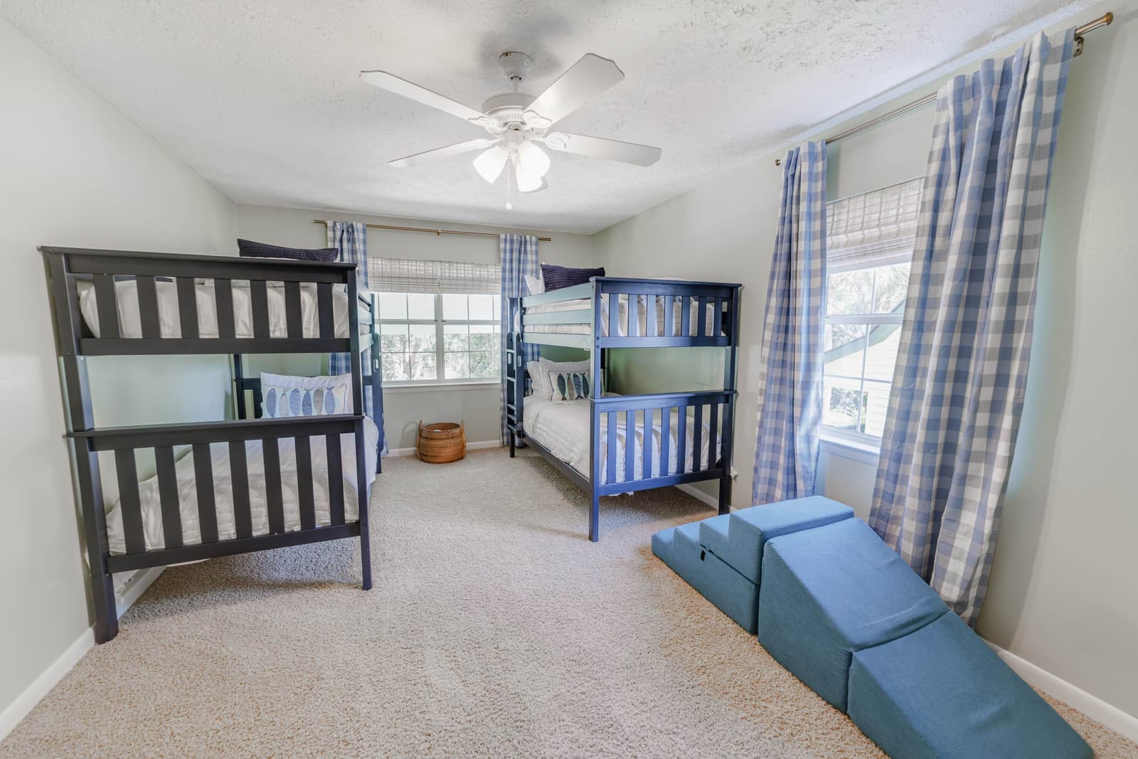 Bunk room with two sets of bunk beds and a foam play climbing set