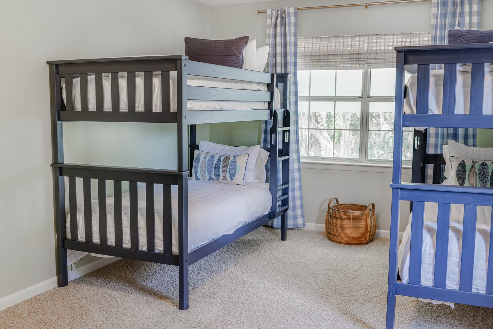 Dark-framed bunk bed beside a window with a woven basket