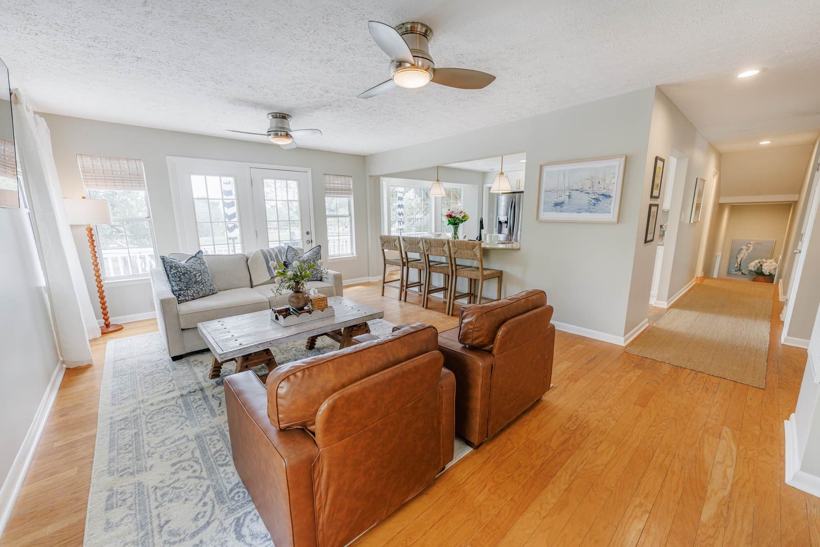 Second living room open to the kitchen and dining table, with leather chairs and a sofa