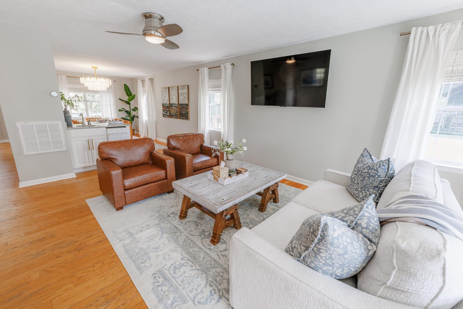 Second living room looking toward the kitchen, with leather chairs, a TV, and a coffee table