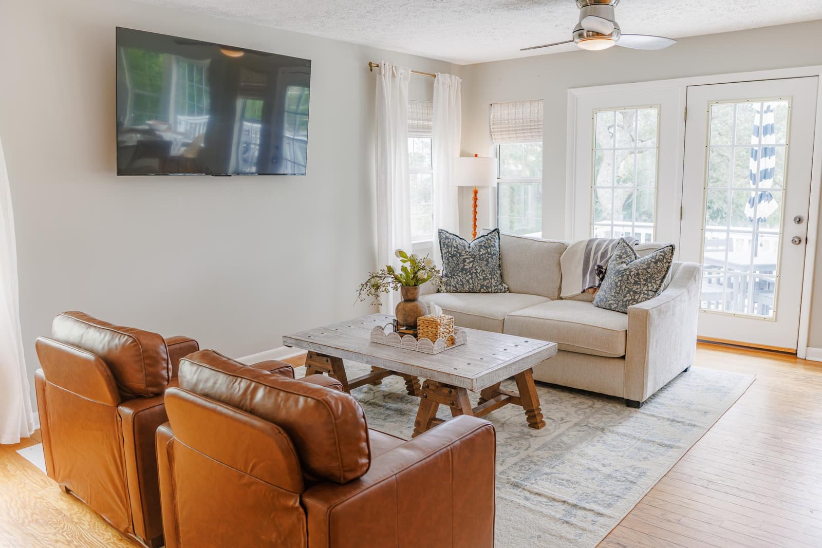 Second living room with a white sofa, leather armchairs, and a wall-mounted TV