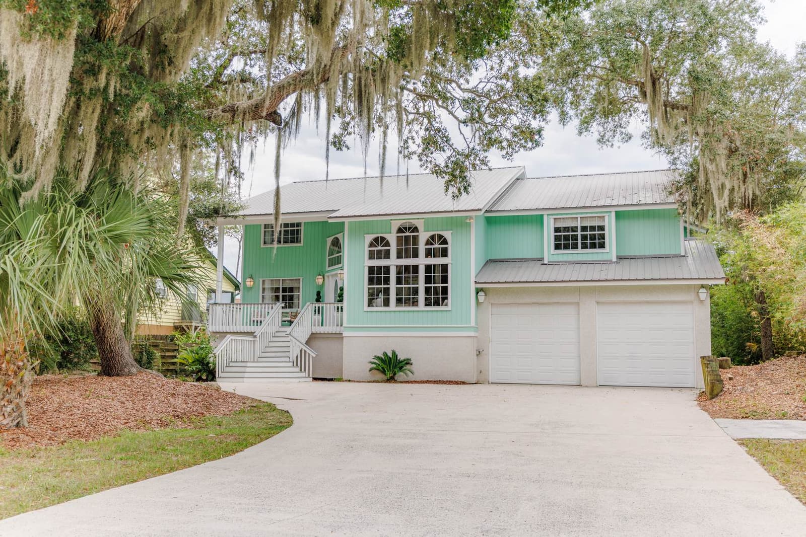 The house seen from the driveway beneath live oaks draped in Spanish moss