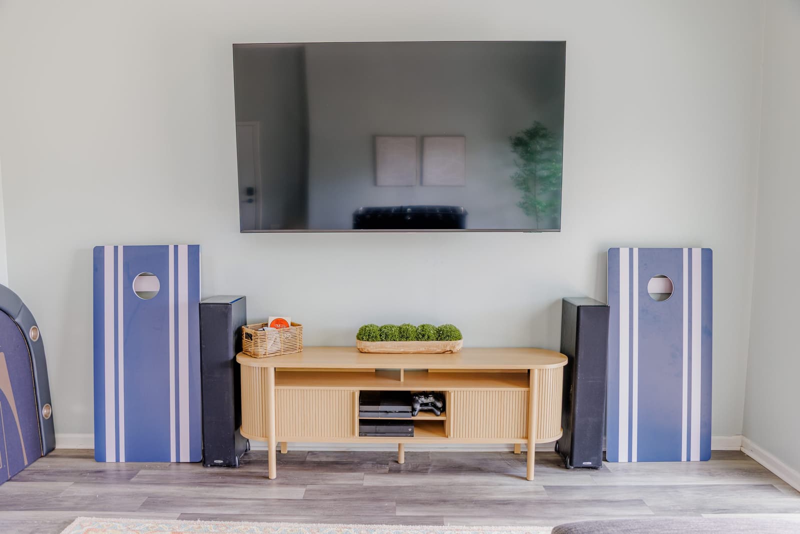 Game room TV on a wood console flanked by blue-striped speakers