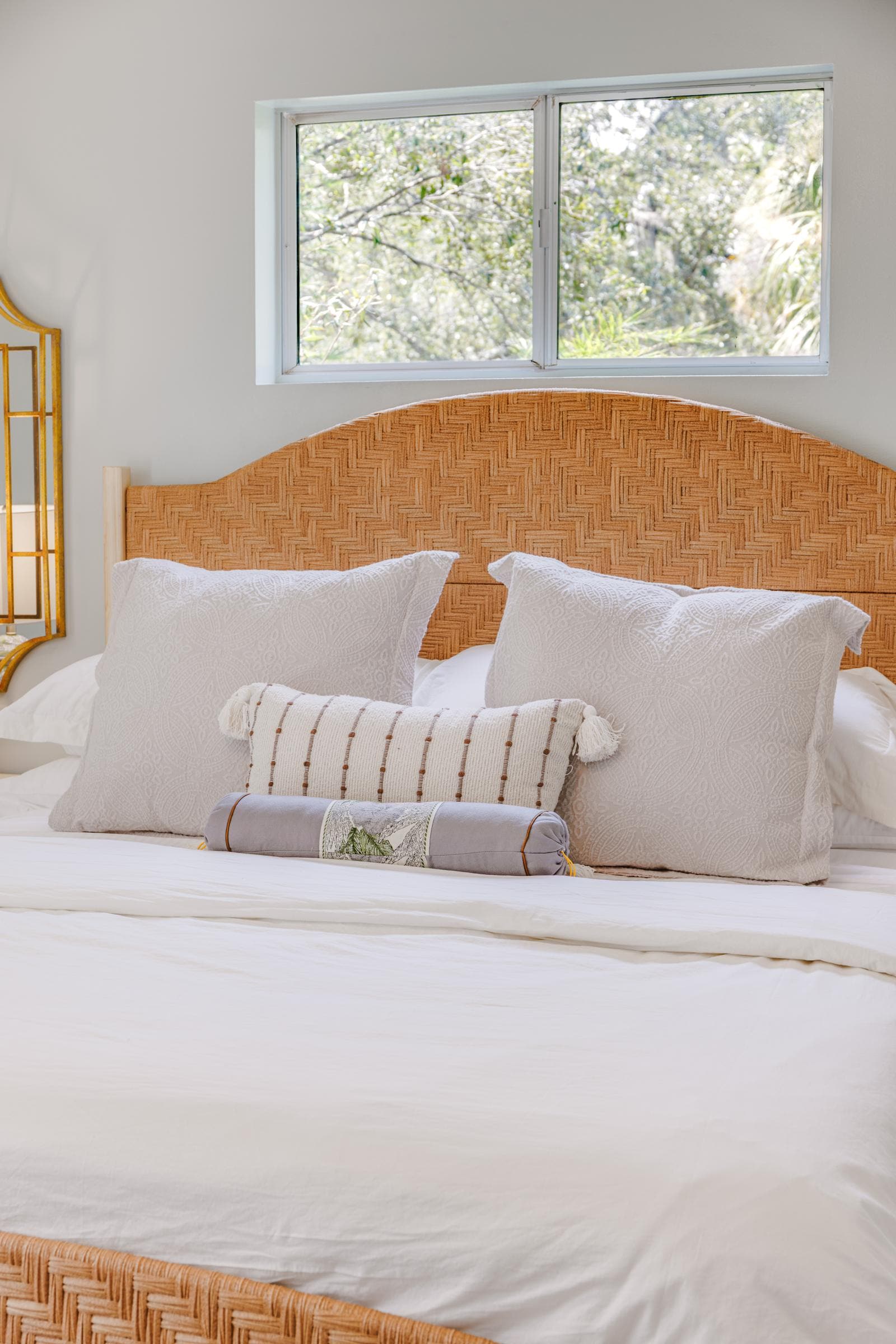 Woven headboard and layered pillows on the classic guest bedroom king bed