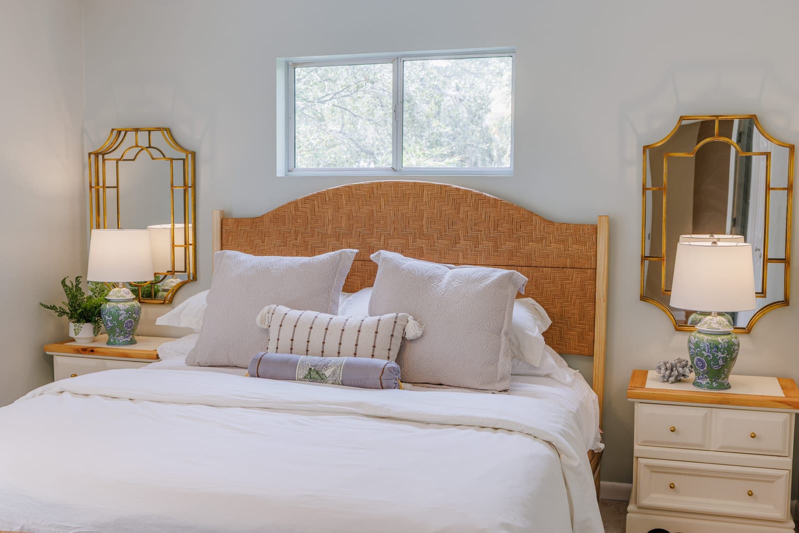 Classic guest bedroom king bed between gold-framed mirrors and lamps