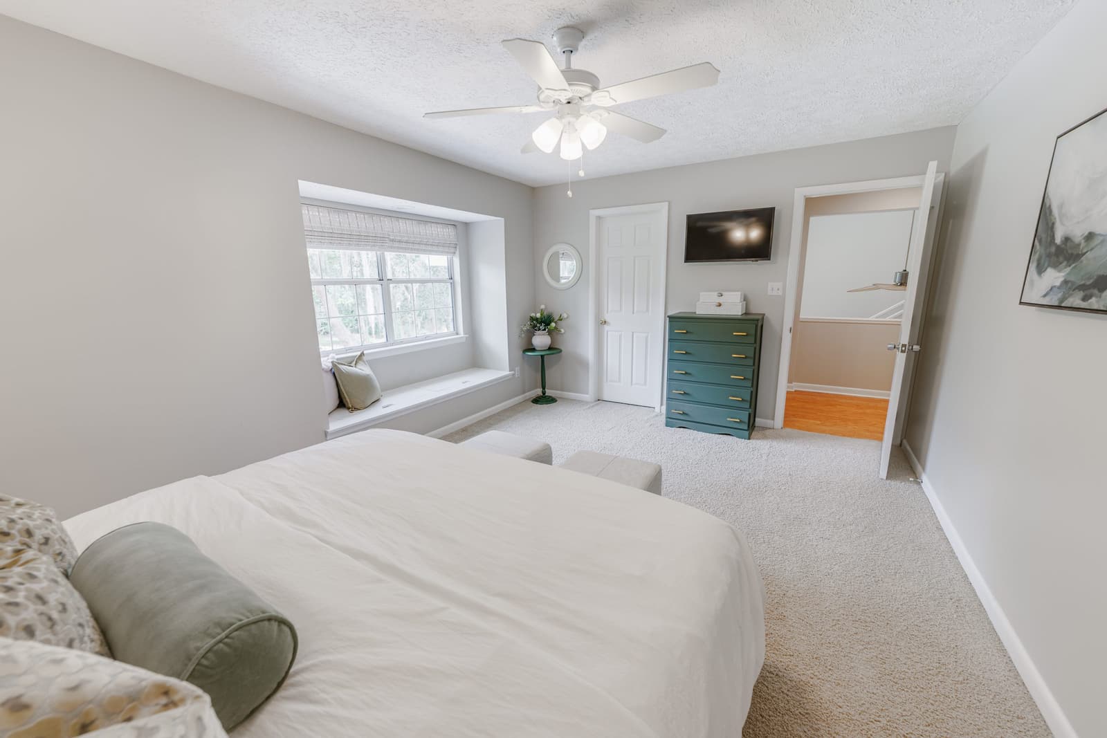 Classic guest bedroom with a king bed, teal dresser, and window seat