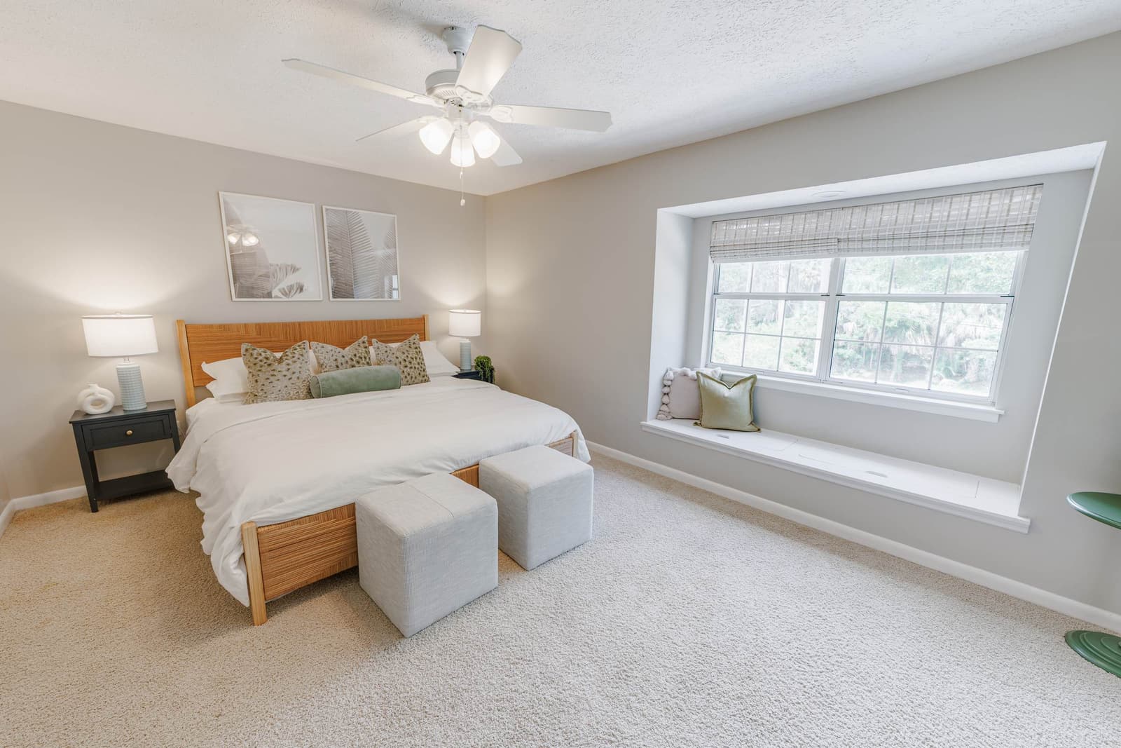 Playful guest bedroom king bed with two gray ottomans and a window bench