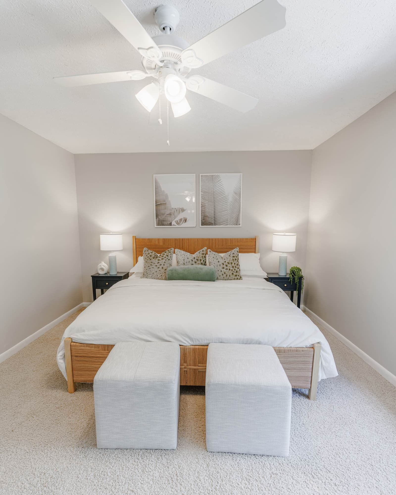 Playful guest bedroom king bed with framed art above and gray ottomans at the foot