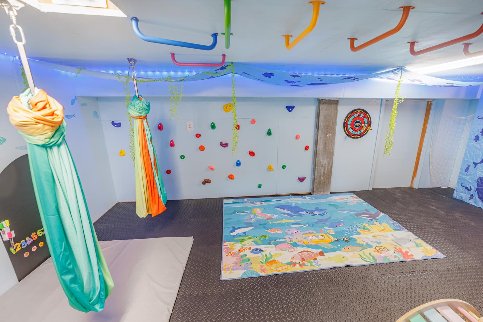 Kids' hideout room with a hanging swing, rock climbing wall, and monkey bars