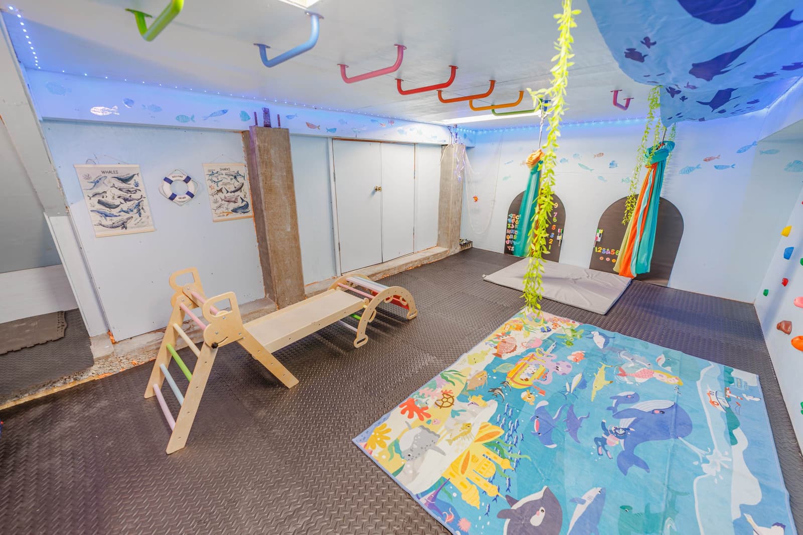 Kids' hideout room with a wooden climbing ramp, play rug, and blue ceiling