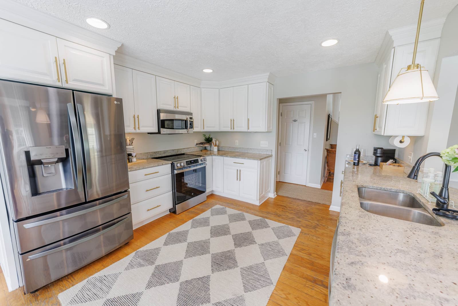 Kitchen with stainless steel appliances, white cabinets, and granite counters