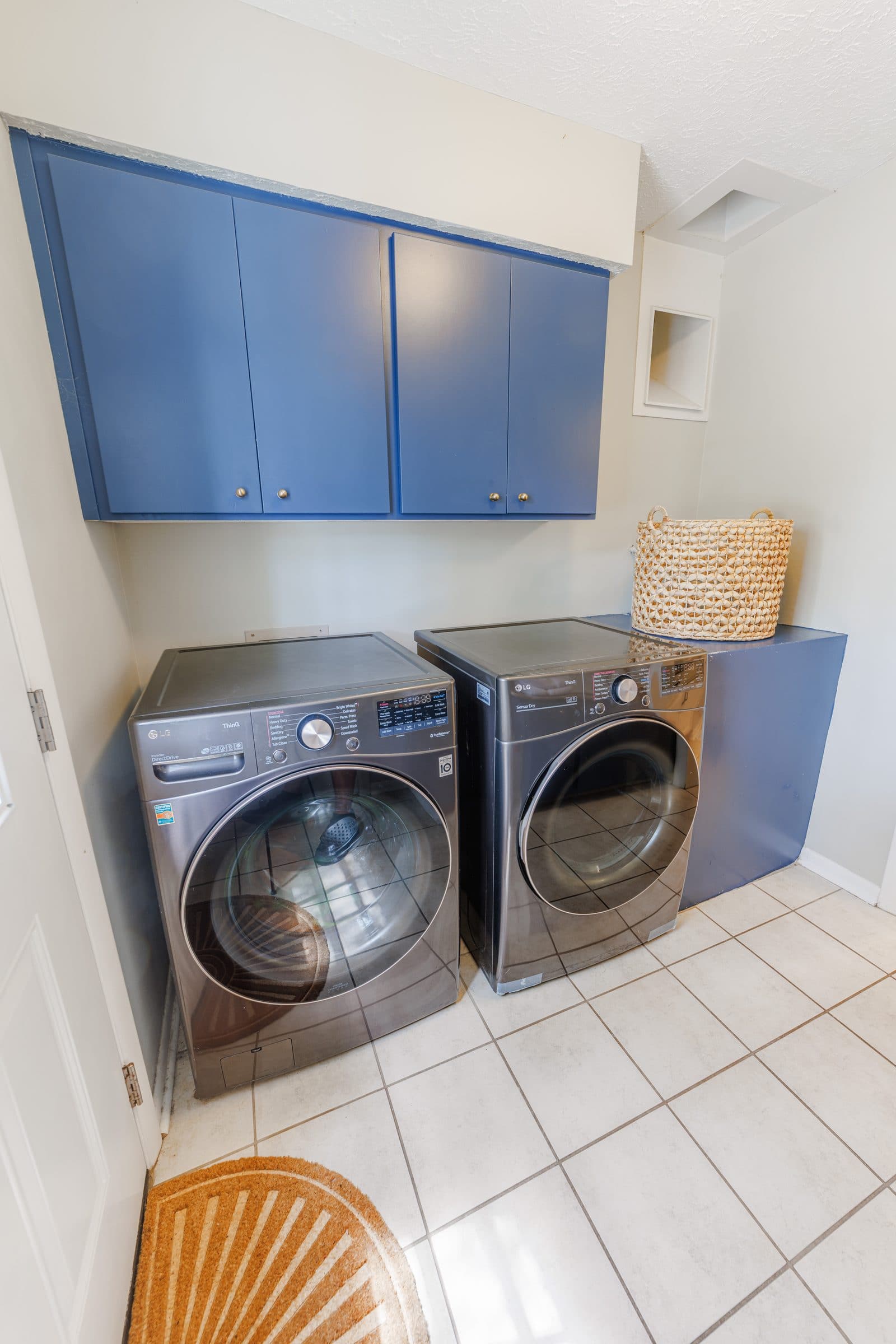 Laundry room with a front-loading washer and dryer under blue cabinets