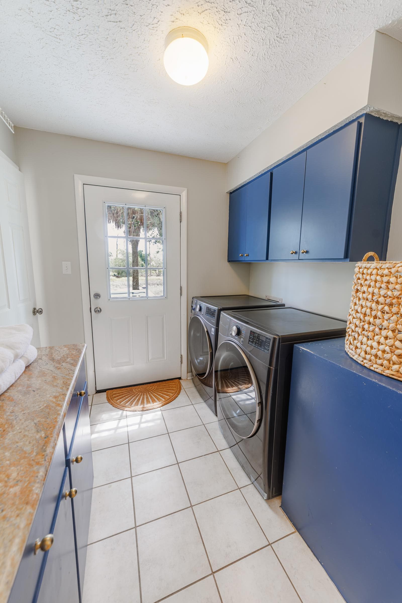 Laundry room with washer, dryer, blue cabinets, and a door to the outside