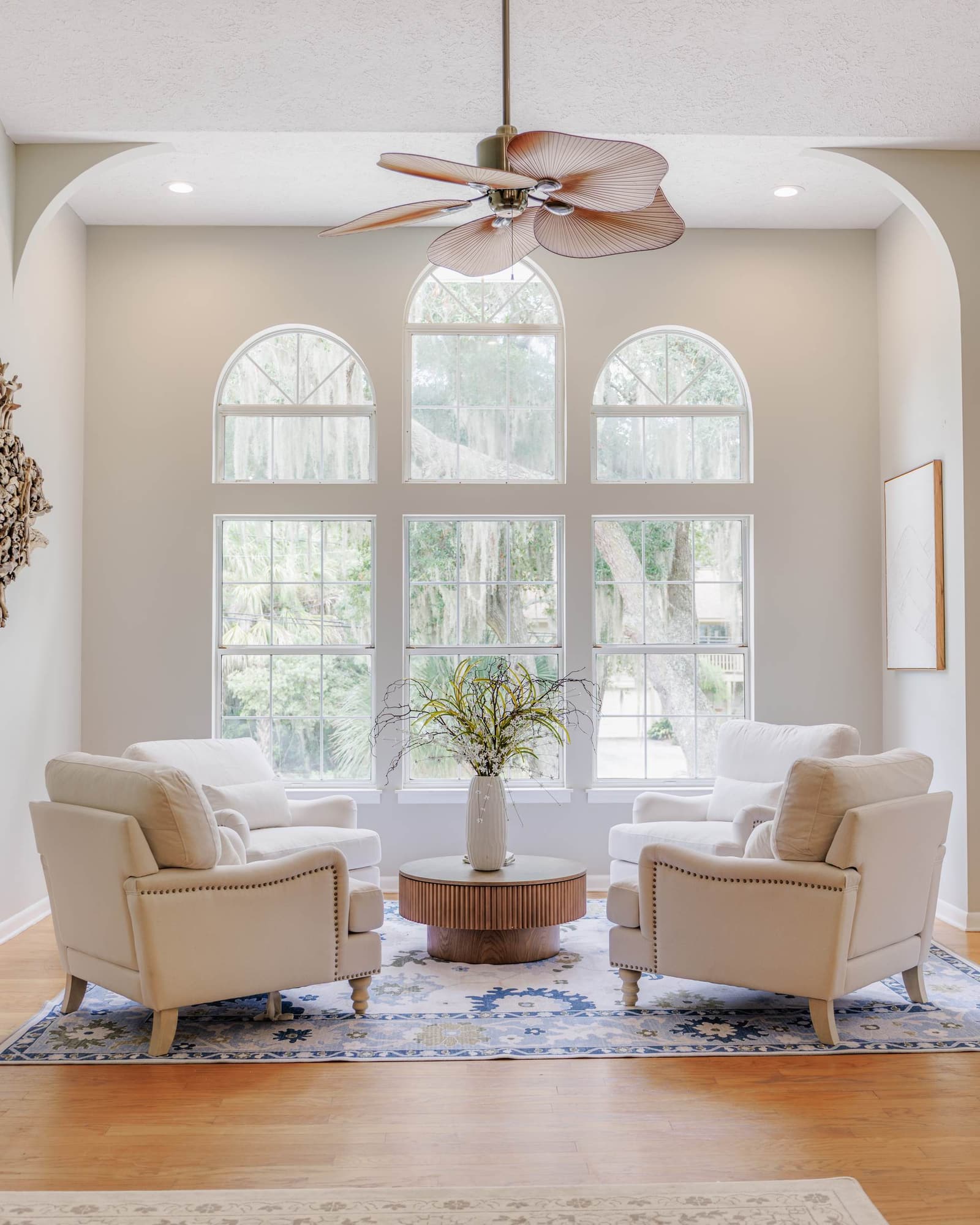 Arched window wall in the living room with a round wood coffee table and two armchairs