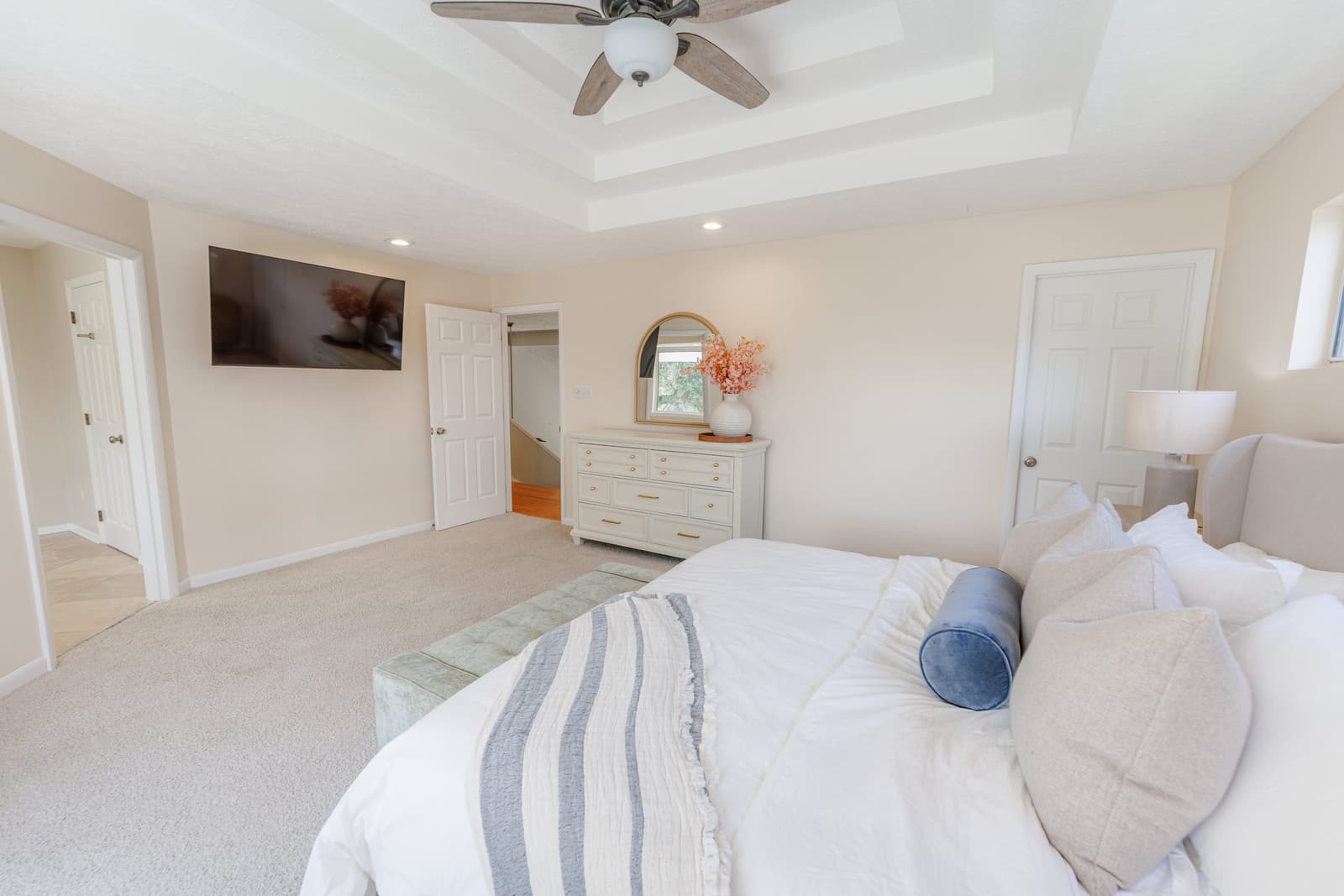 Primary suite bed with blue-striped linens, a TV, and a dresser