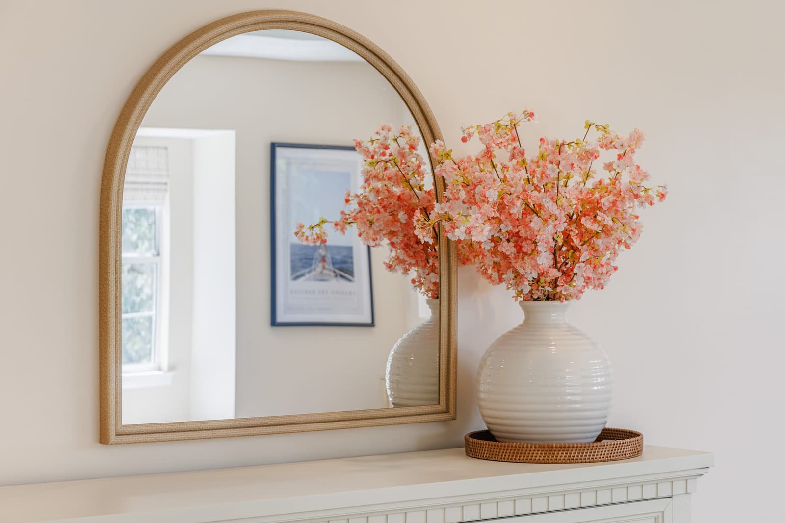 Arched gold mirror and pink flowers on the primary suite dresser